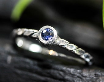 Dainty silver band with round faceted blue sapphire gemstone in bezel setting