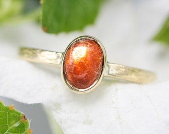 Oval cabochon sunstone ring in bezel setting with 18k gold texture band