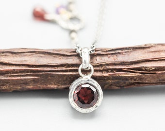 Round faceted red garnet pendant necklace in silver bezel setting with sterling silver chain