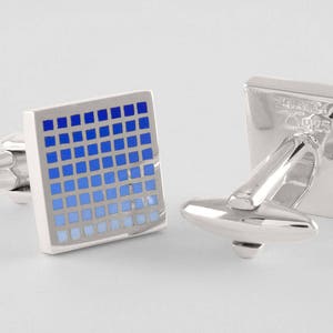 May include: A pair of silver cufflinks with a blue gradient pattern. The pattern is made up of small squares.