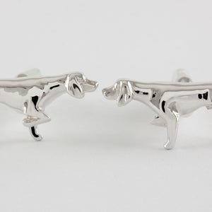May include: A pair of silver cufflinks featuring a detailed, three-dimensional design of a pointing dog.