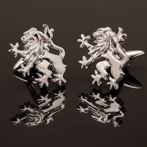 May include: A pair of silver cufflinks featuring a lion design. The lions are facing forward with their paws raised.