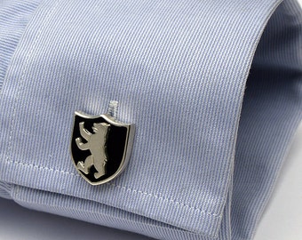 May include: Silver cufflinks with a black enamel shield featuring a silver bear.