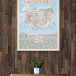 May include: A framed poster with a blue and white background featuring a movie poster for the film "Caddyshack". The poster is made up of tiny words and the title of the film is in red letters.