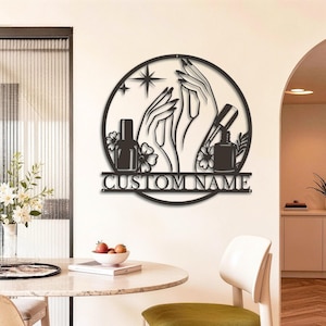 Op de afbeelding: Zwart metalen nail art bord met handen, nagellakflesjes en bloemen in een cirkelvormig ontwerp. Het bord bevat de tekst "CUSTOM NAME" eronder, perfect voor een nagelsalon of schoonheidssalon.