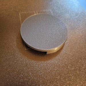 May include: A gray 3D printed round object with a textured surface. The object has a small opening on the side.