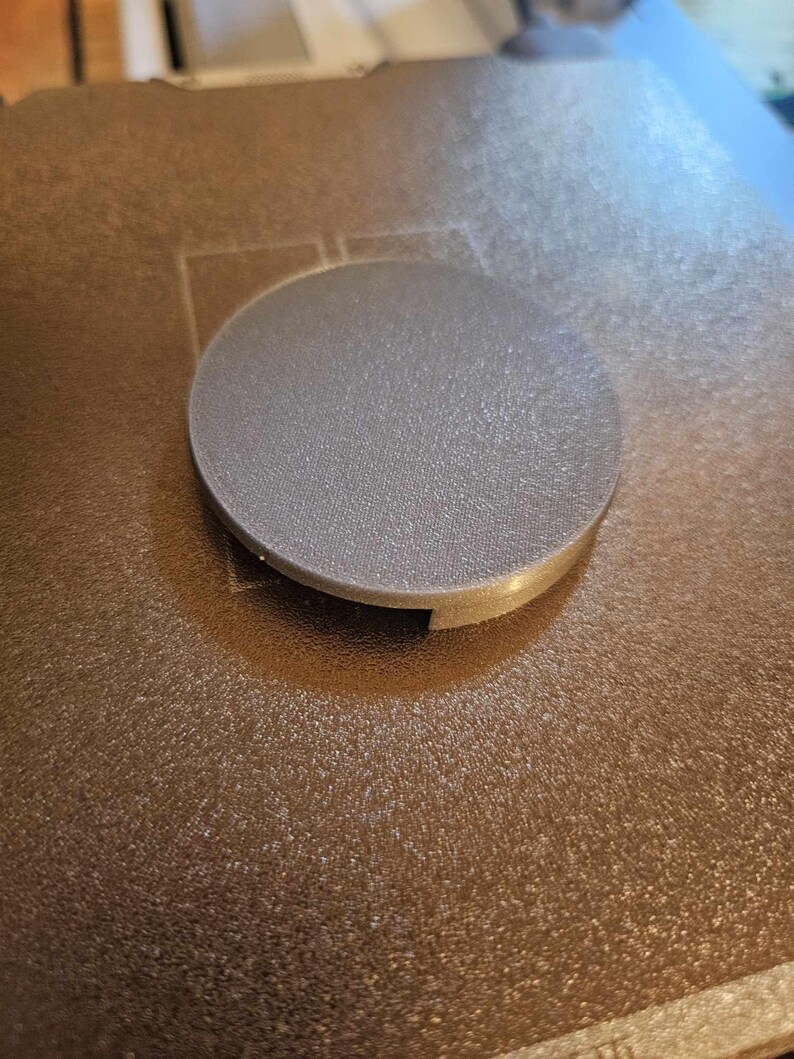 May include: A gray 3D printed round object with a textured surface. The object has a small opening on the side.