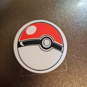 May include: A white and red Pokeball with a black outline and a black stripe across the middle. The Pokeball has a white circle in the center.