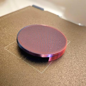 May include: A round, red and black, textured, 3D printed object.
