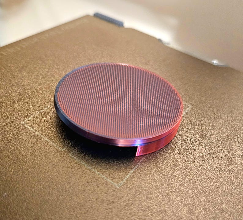 May include: A round, red and black, textured, 3D printed object.