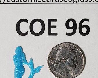 May include: A small, light blue, translucent mermaid-shaped glass piece next to a United States quarter coin for scale. The text "COE 96" and a partial web address are printed in black above the mermaid and the coin on a white background.