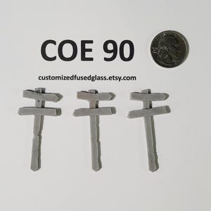 May include: Three gray glass signposts with two arms each, pointing in different directions. The signposts are approximately 1 inch tall. The text "COE 90" and the website "customizedfusedglass.etsy.com" are visible below the signposts.