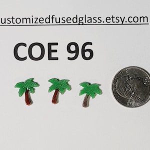 May include: Three small, green and brown palm tree charms next to a quarter coin on a white surface. The text "COE 96" is above the charms. The Etsy shop URL is at the top.
