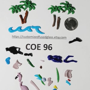 Peut inclure: Divers éléments en verre fusionné coloré, dont des palmiers, des vagues, un flamant rose et d'autres formes. Le texte "COE 96" est visible, ainsi qu'une adresse de site web. Une pièce de monnaie est incluse pour la référence de taille.
