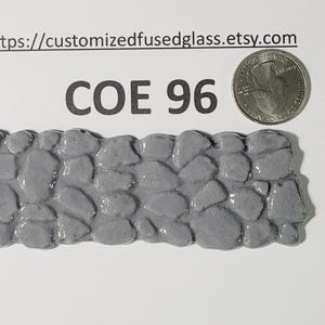 May include: A gray fused glass piece resembling a stone wall, with a quarter coin for size comparison. The text "COE 96" is printed above the glass. The Etsy shop URL is also visible.