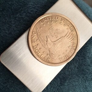 A handmade coin money clip made with a stainless steel money clip and a UNITED states of America dollar coin.