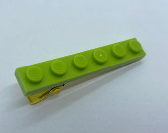 May include: A lime green hair clip shaped like a row of five Lego bricks.