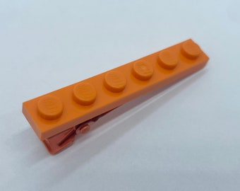 May include: Orange plastic hair clip shaped like a row of five Lego bricks.