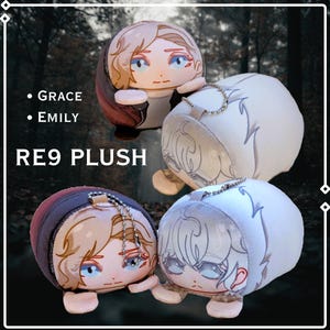 Op de afbeelding: Vier ronde knuffels met geprinte gezichten in anime-stijl en kleine ledematen. Twee hebben lichtbruin haar en donkere kleding, terwijl twee wit haar en lichte kleding hebben. Elke knuffel is voorzien van een zilveren metalen kogeltjesketting.