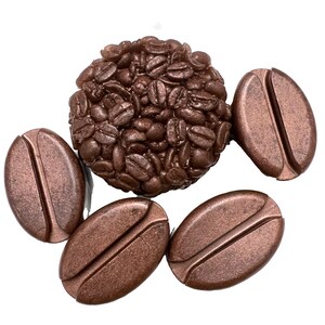 May include: A cluster of brown coffee bean-shaped beads and a central round bead cluster. The beads have a metallic finish and are arranged on a white background. The design evokes a coffee theme.