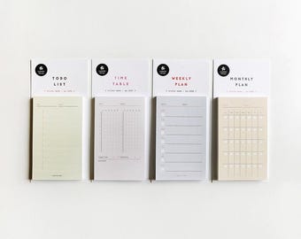 May include: Four sticky note pads for planning, labelled "Todo List", "Time Table", "Weekly Plan", and "Monthly Plan". Each pad has a different layout, with lines, grids, and a calendar format. The pads are in shades of beige, grey, and white. The pads are attached to white backing cards.