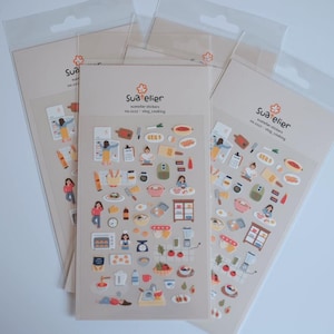 May include: Several sticker sheets featuring cooking-themed illustrations. Each sheet displays various kitchen items, food, and people cooking. The text "Sua atelier" and "vlog_cooking" are visible on the packaging.