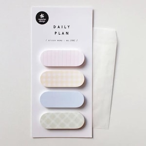 May include: A set of pastel-colored sticky memo pads with a white backing. The pads are oval-shaped and feature various patterns, including stripes and checks. The text "DAILY PLAN" is printed on the backing, along with the brand logo and "STICKY MEMO NO.1982".