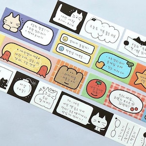 Puede incluir: Un conjunto de cintas adhesivas washi de colores con varias ilustraciones, incluyendo gatos, una bomba, un fantasma, un tomate, una estrella y un bocadillo de diálogo con el texto "MEOW". La cinta está diseñada para usar en planificadores, diarios y otras manualidades de papel.