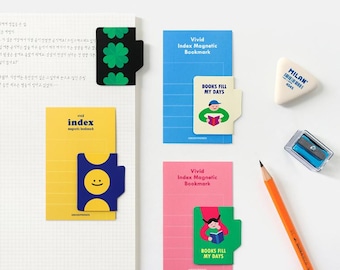 Op de afbeelding: Een verzameling kleurrijke magnetische bladwijzers en briefpapier. De bladwijzers hebben verschillende ontwerpen, waaronder een klavertje vier, een smiley en illustraties van mensen die boeken lezen. Een potlood, gum en puntenslijper zijn ook aanwezig.