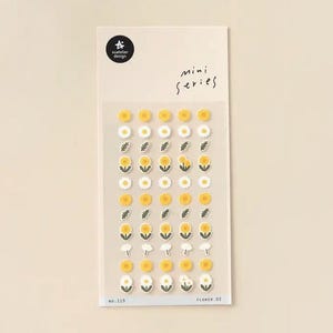 Puede incluir: Una hoja de pegatinas con temática floral. Las pegatinas presentan diseños de margaritas y girasoles amarillos y blancos, junto con acentos de hojas verdes. La hoja tiene el texto "mini series" y "suatelier design".