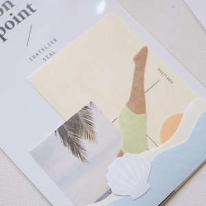 May include: A collection of decorative paper elements, including a postcard with a figure in a handstand, a palm tree image, and a seashell cutout. The words "on point" and "SUATELIER SEAL" are printed on the top left.