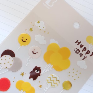 May include: Sheet of decorative stickers with balloons, clouds, stars, and a brown bear. The stickers are in yellow, red, and brown. The text "HAPPY :DAY" is printed in brown.