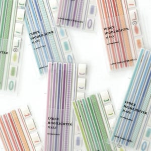 May include: A collection of index highlighter markers in clear plastic packaging. The markers feature various pastel colors and patterns, with text that reads "Index Highlighter Mark" and "30 Sheets Each". The color palette includes shades of green, blue, purple, and orange.