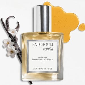 May include: A square glass bottle of perfume oil with a silver cap and a label reading PATCHOULI vanilla, perfume oil, handcrafted | small batch, 1 OZ, DST FRAGRANCES. The bottle is surrounded by dark vanilla bean pods, white flowers, and amber liquid.