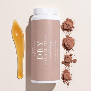 May include: A white and tan dry shampoo bottle with the text "DRY SHAMPOO" and "cacao honey". The image also shows a brown powder and a golden applicator. The bottle contains 4.02 oz of product.