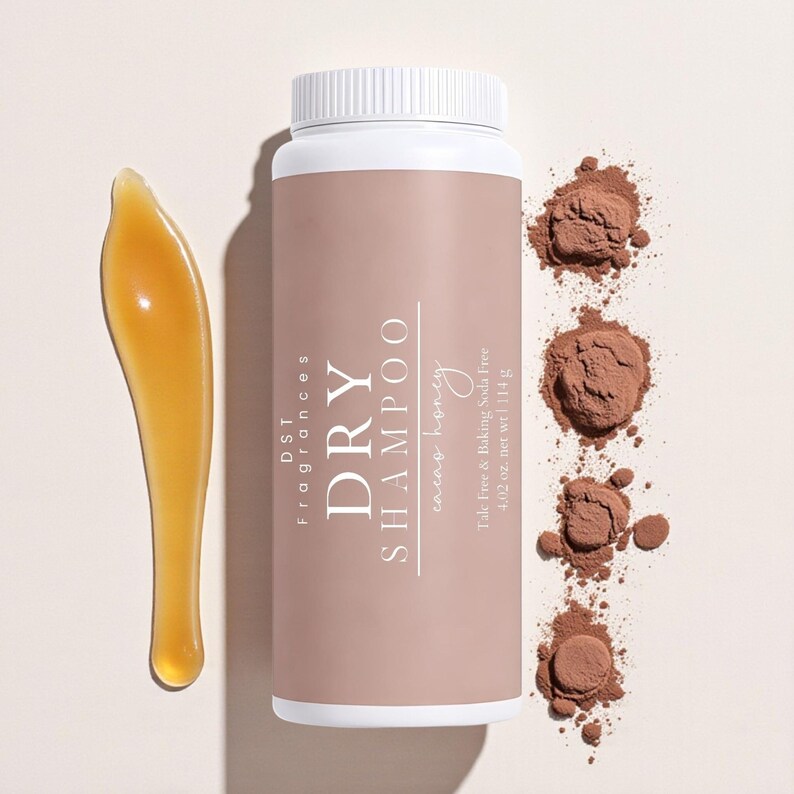 May include: A white and tan dry shampoo bottle with the text "DRY SHAMPOO" and "cacao honey". The image also shows a brown powder and a golden applicator. The bottle contains 4.02 oz of product.