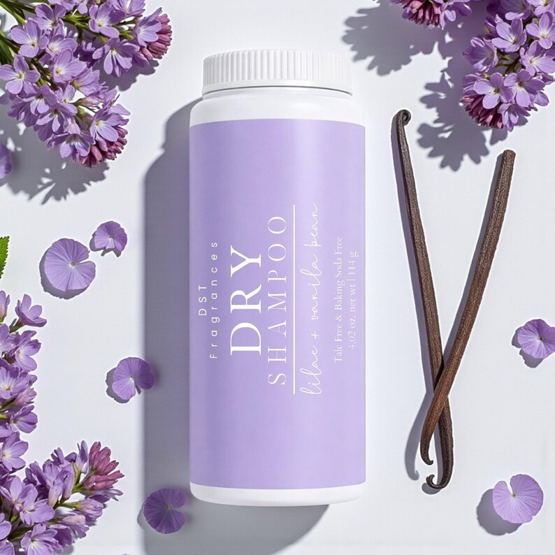 May include: A white and purple dry shampoo bottle with the text "DRY SHAMPOO" and "lilac + vanilla bean". The bottle is surrounded by purple flowers and two vanilla beans. The bottle contains 4.02 oz. net wt.
