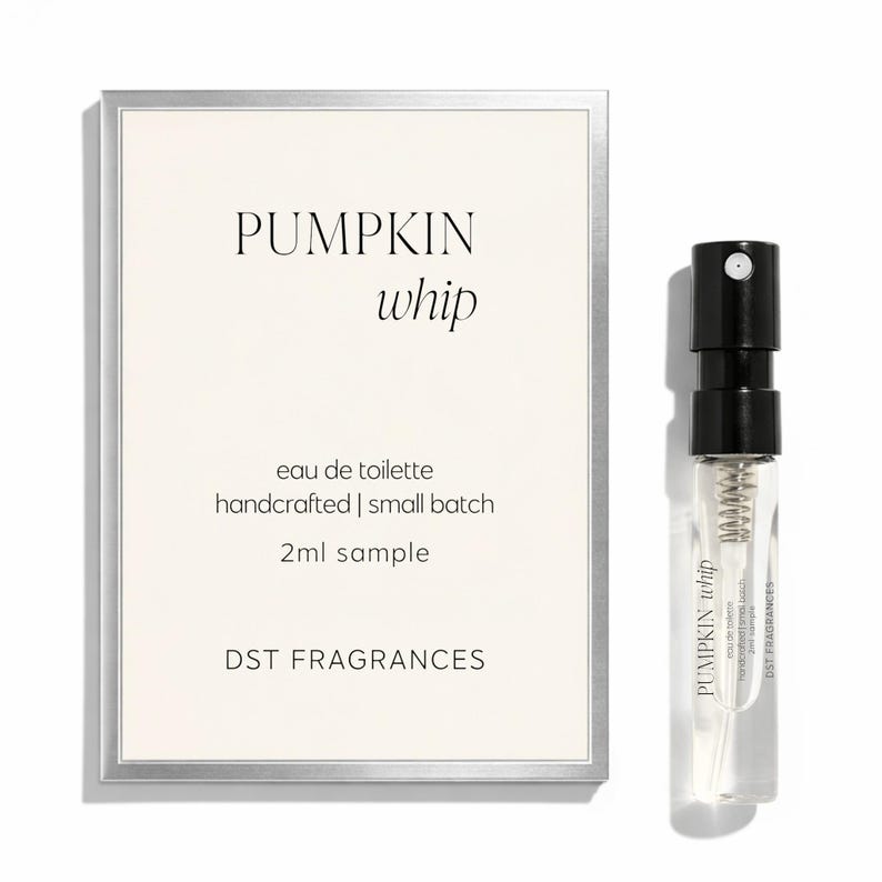 May include: A rectangular card with a silver border featuring the text PUMPKIN whip, eau de toilette, handcrafted | small batch, 2ml sample, and DST FRAGRANCES, alongside a clear glass 2ml spray vial with a black cap and a label reading PUMPKIN whip.