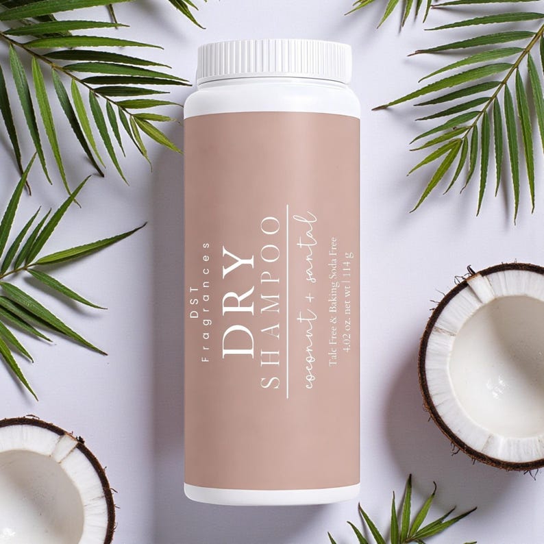 May include: A white and tan dry shampoo bottle with the text "DRY SHAMPOO coconut + santal". The bottle is surrounded by green palm leaves and coconut halves. The bottle contains 4.02 oz. net wt | 114 g.