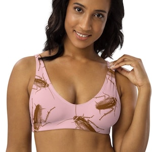 May include: A pink sports bra with a pattern of brown cockroaches. The bra has a V-neck and adjustable straps.