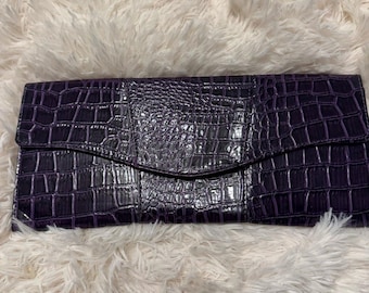 Elegante bolso de mano morado con relieve de cocodrilo.