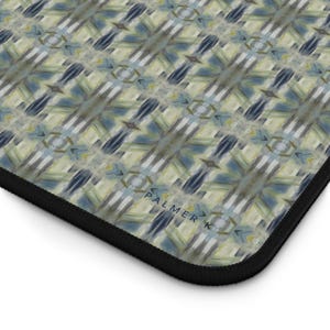 Op de afbeelding: Een muismat met een geometrisch patroon in tinten blauw, groen en wit. Het patroon is een herhalend ontwerp van vierkanten en driehoeken. De muismat heeft een zwarte rand en de tekst "PALMER K" is afgedrukt in de rechterbenedenhoek.