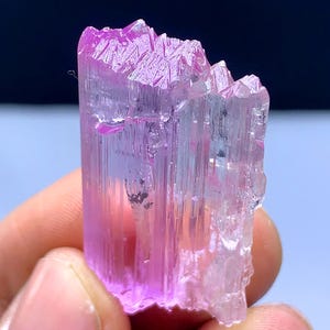 Peut inclure: Un cristal rose et transparent avec une texture stri&eacute;e. Le cristal est translucide et a une l&eacute;g&egrave;re teinte rose.