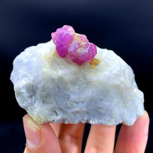 以下が含まれることがあります： 白いマトリックスの上にピンクのルビーの結晶の塊。ルビーの結晶は半透明で、ガラスのような光沢があります。マトリックスはざらざらしていて、白いです。