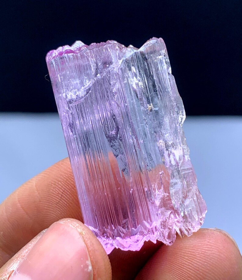 Peut inclure: Un cristal allong&eacute; facett&eacute; rose et transparent avec des stries. Le cristal est translucide et a une l&eacute;g&egrave;re teinte rose.