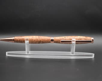 May include: A handcrafted wooden pen with a light brown, patterned finish and copper-colored accents. The pen is displayed on a clear acrylic stand, showcasing its elegant design. A sophisticated writing instrument.