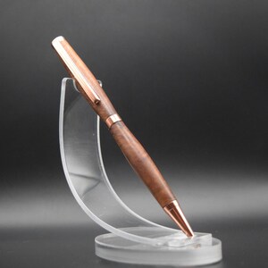 May include: A wooden pen with a copper finish and a clear acrylic pen stand.