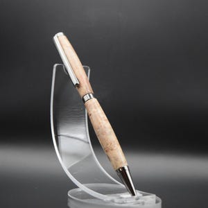 Op de afbeelding: Een houten pen met een zilveren rand, getoond op een transparante kunststof standaard. De pen heeft een lichtbruine kleur met donkerbruine swirls.