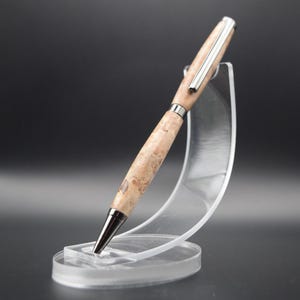 Op de afbeelding: Een houten pen met een zilveren rand, getoond op een transparante plastic standaard. De pen heeft een natuurlijk houtnerfpatroon.