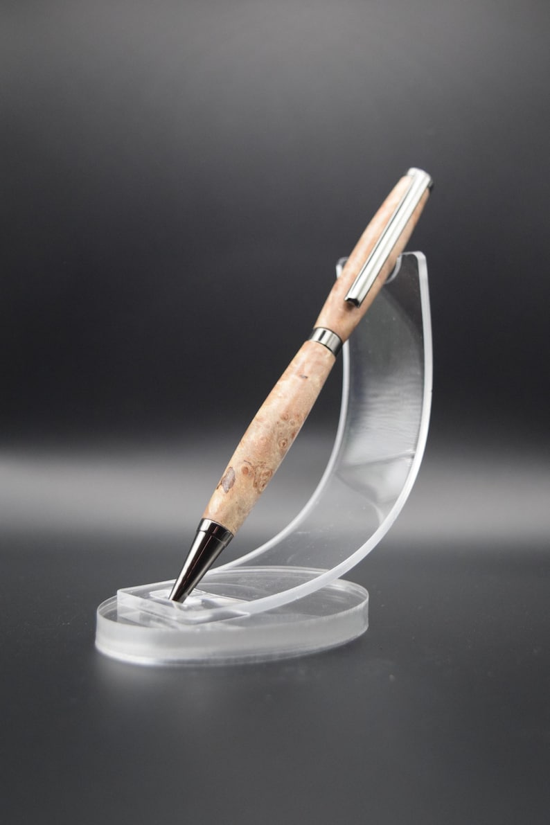 Op de afbeelding: Een houten pen met een zilveren rand, getoond op een transparante plastic standaard. De pen heeft een natuurlijk houtnerfpatroon.